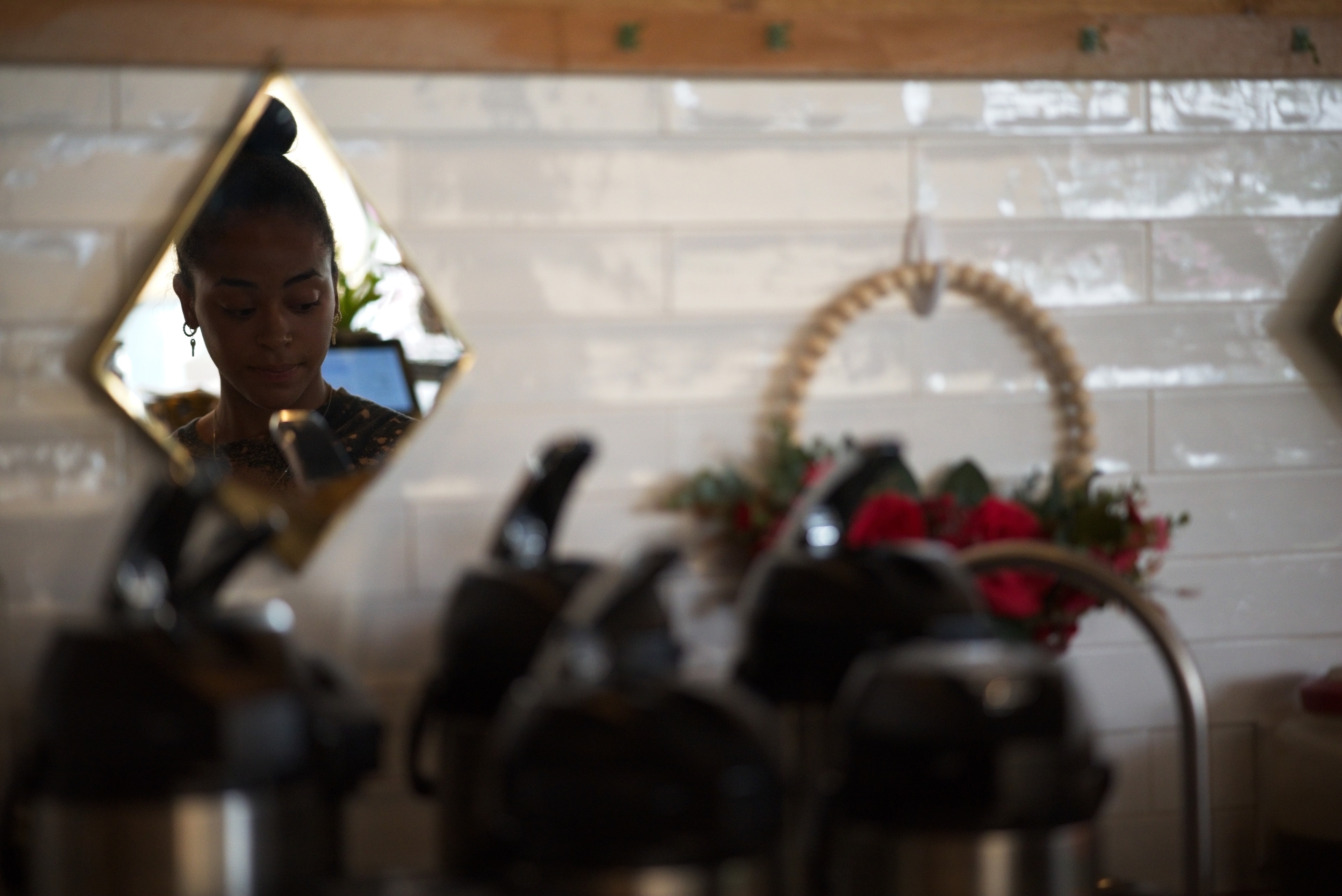 Barista reflected in a diamond-shaped mirror above a coffee bar