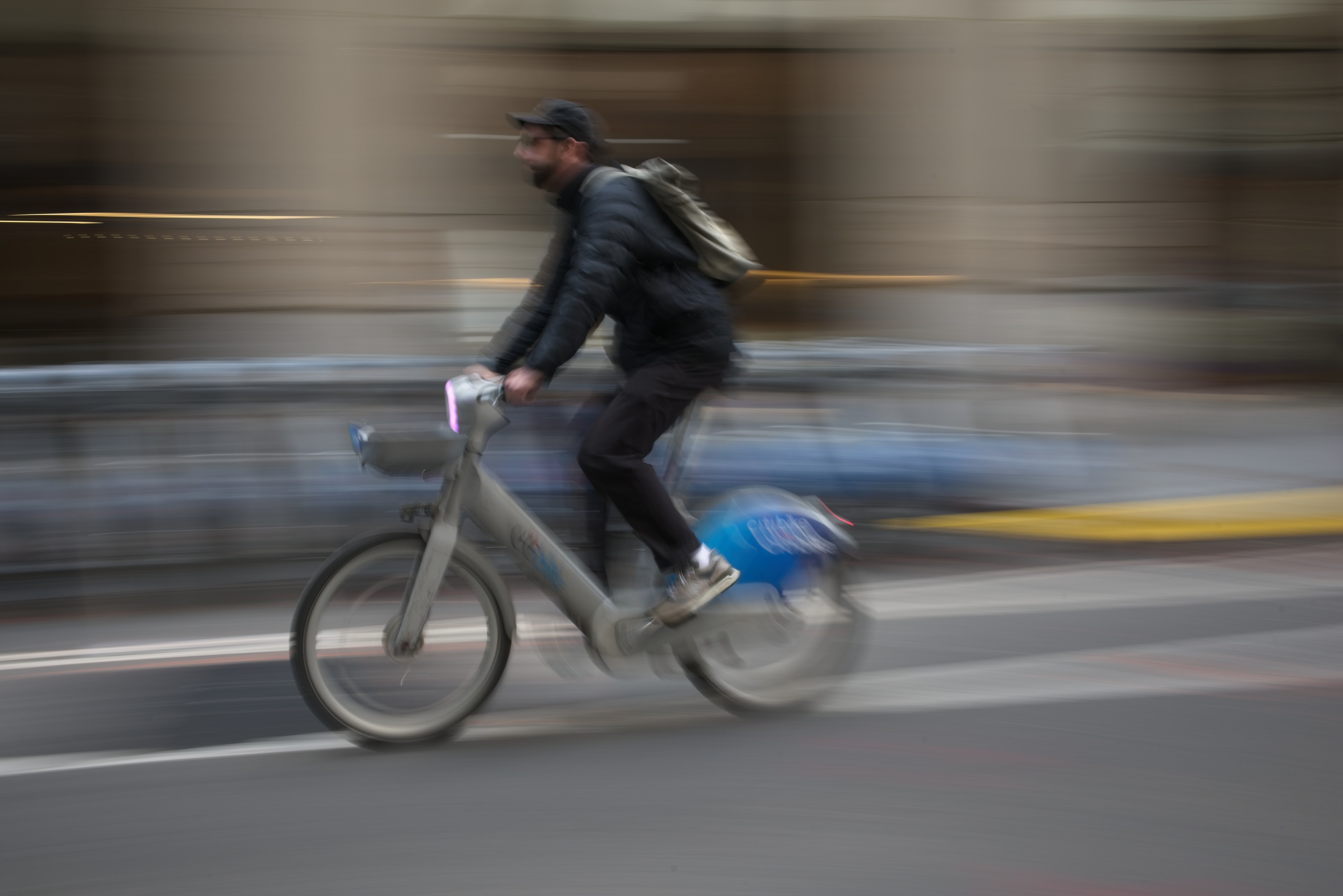 Motion-blurred cyclist on a Citi Bike races through a city street