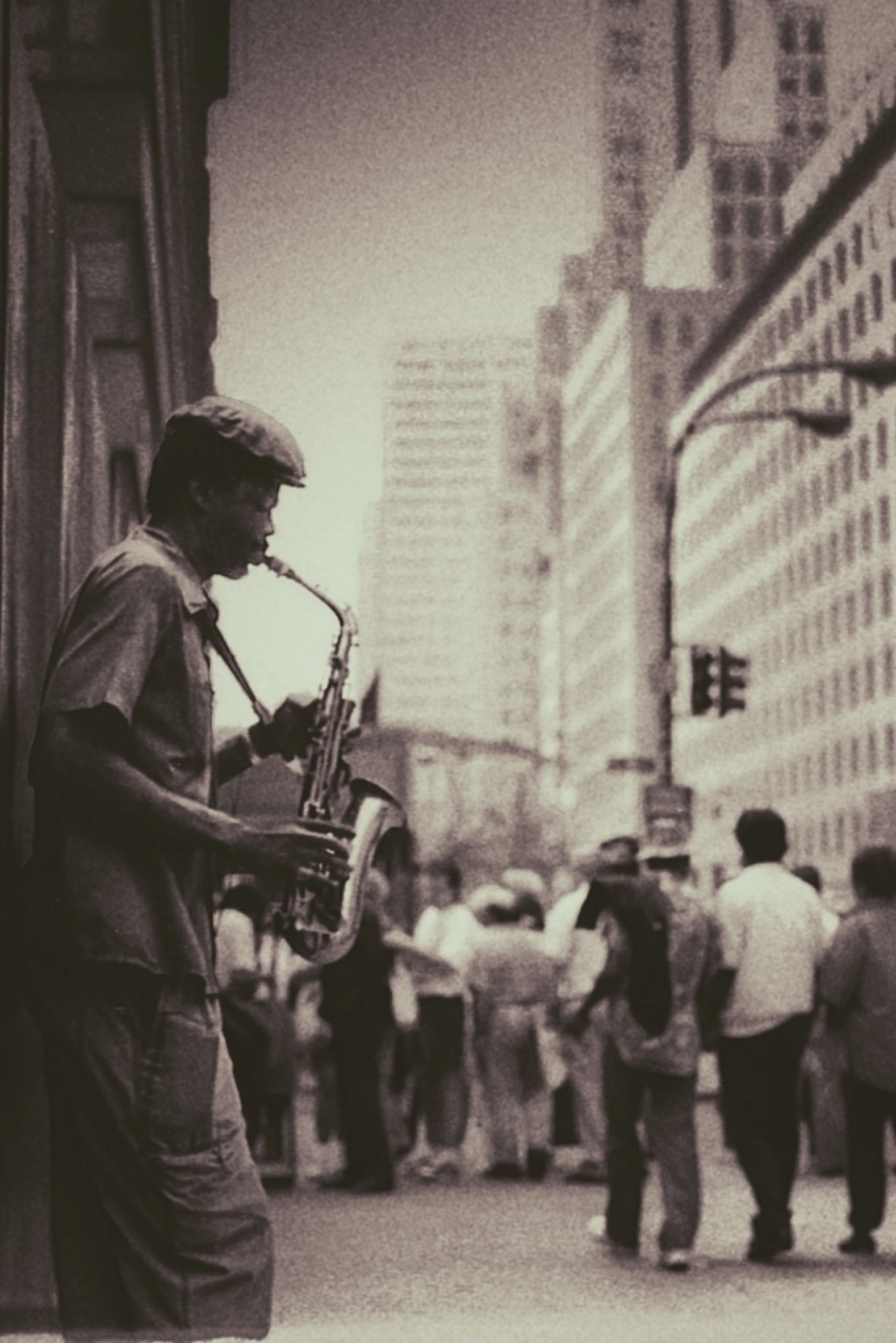 Vintage film photograph of a saxophonist playing on a busy city sidewalk with a crowd streaming past behind him
