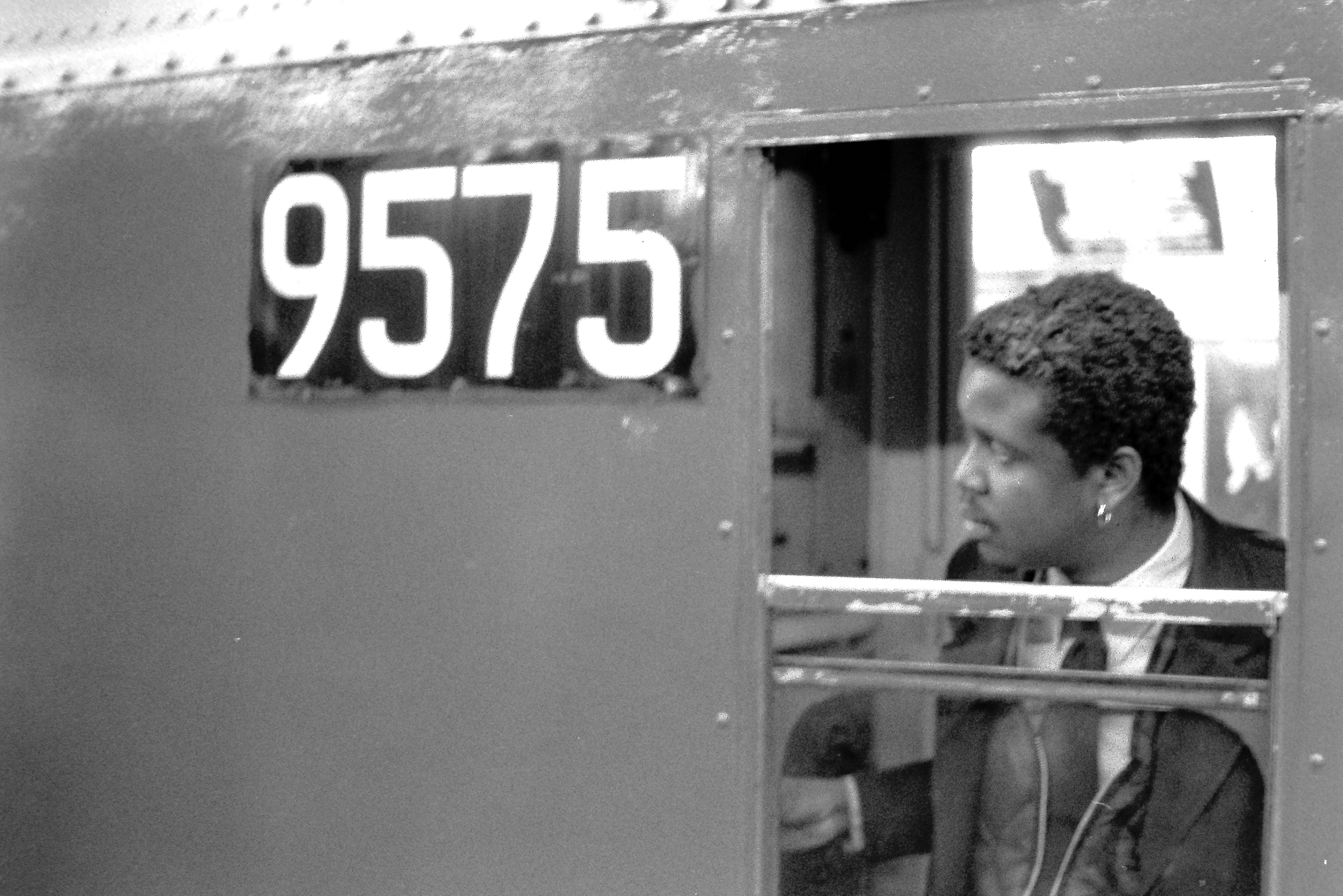 Black and white film photograph of a woman looking out the window of subway car 9575